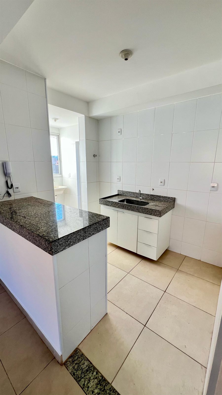 Cozinha com bancadas de granito e área de serviço separada