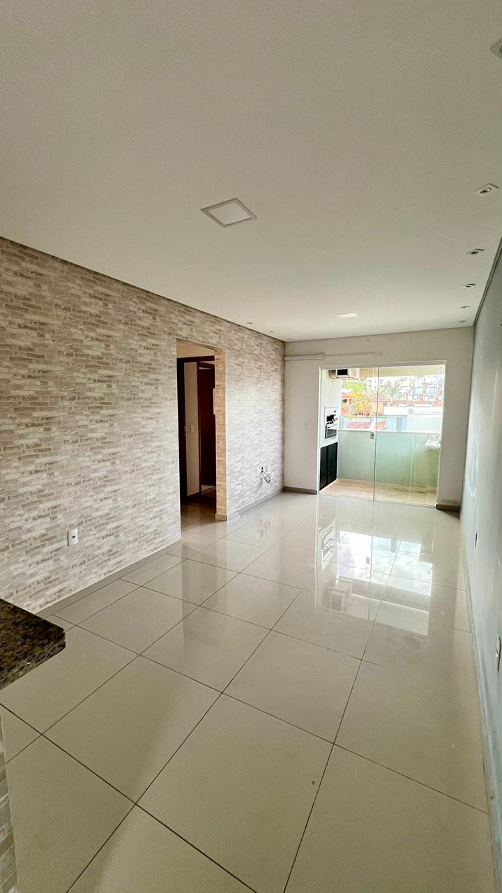 Sala ampla com parede em pedra e saída para a área gourmet