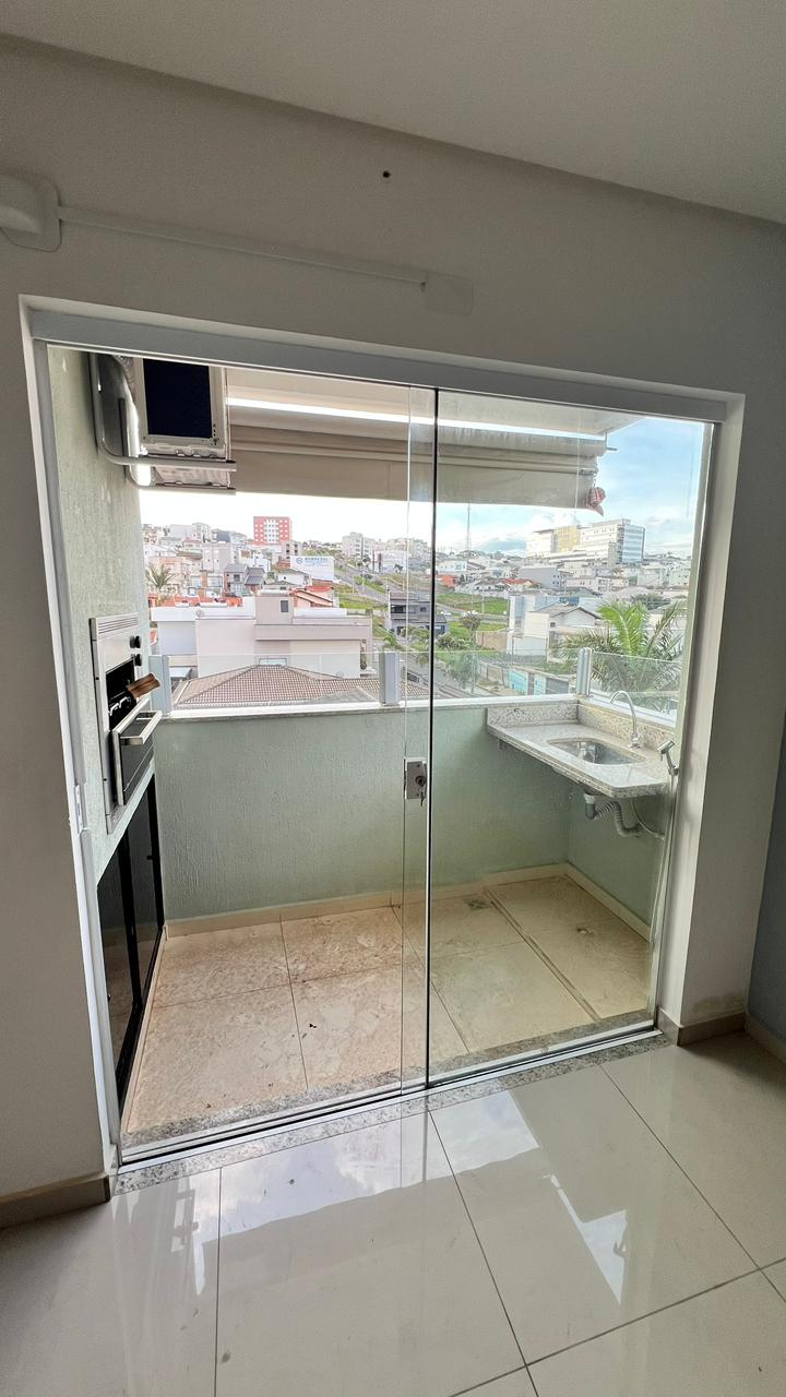Área gourmet envidraçada com churrasqueira e vista da cidade