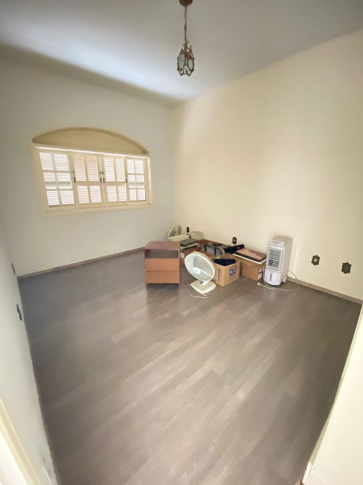 Quarto com piso laminado e janela em arco