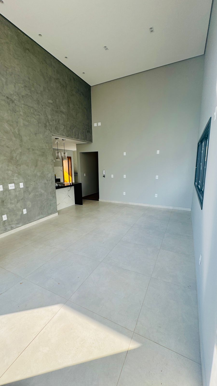 Sala ampla com pé-direito alto e parede em cimento queimado