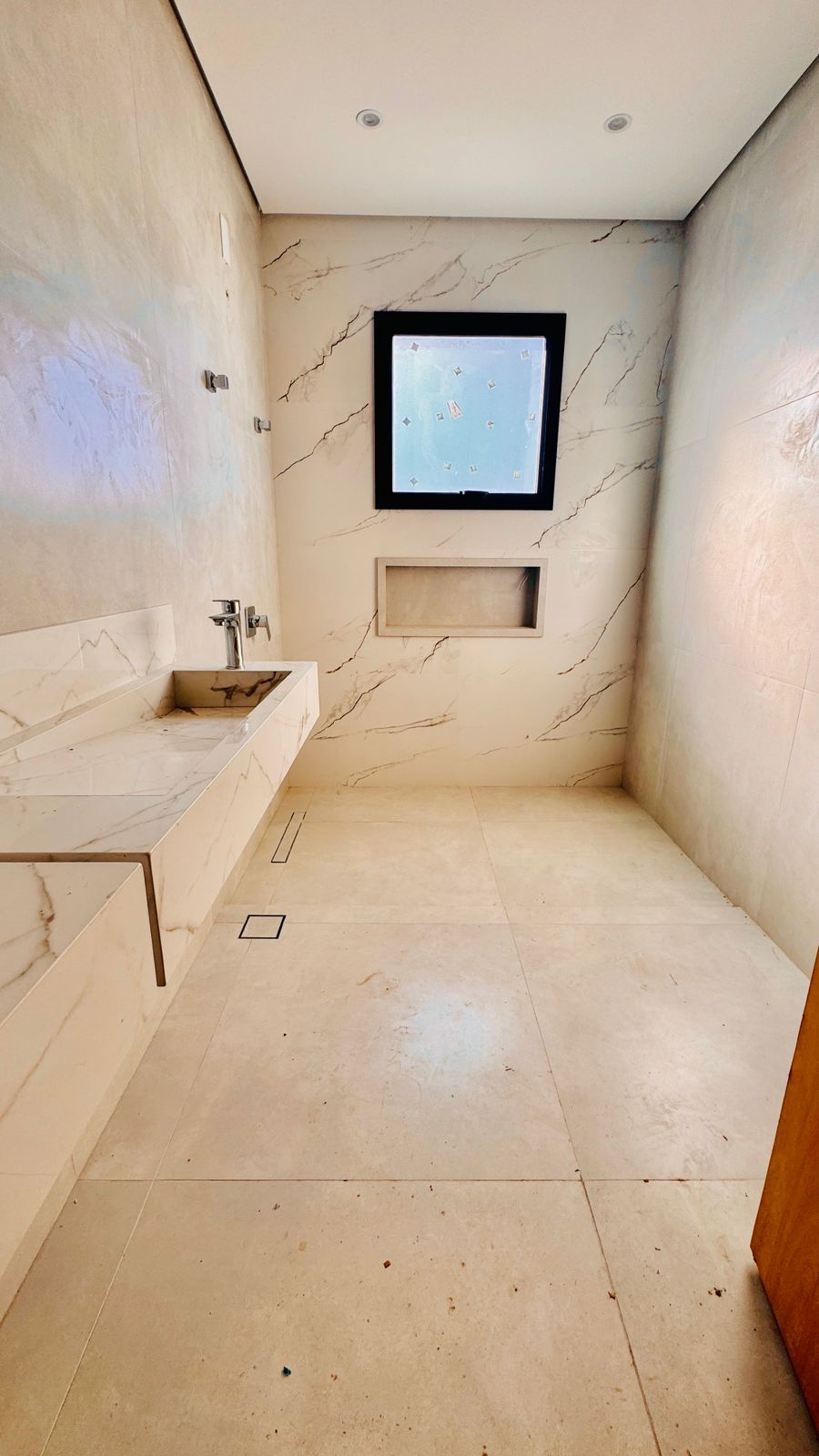 Banheiro da suíte com bancada esculpida em porcelanato marmorizado