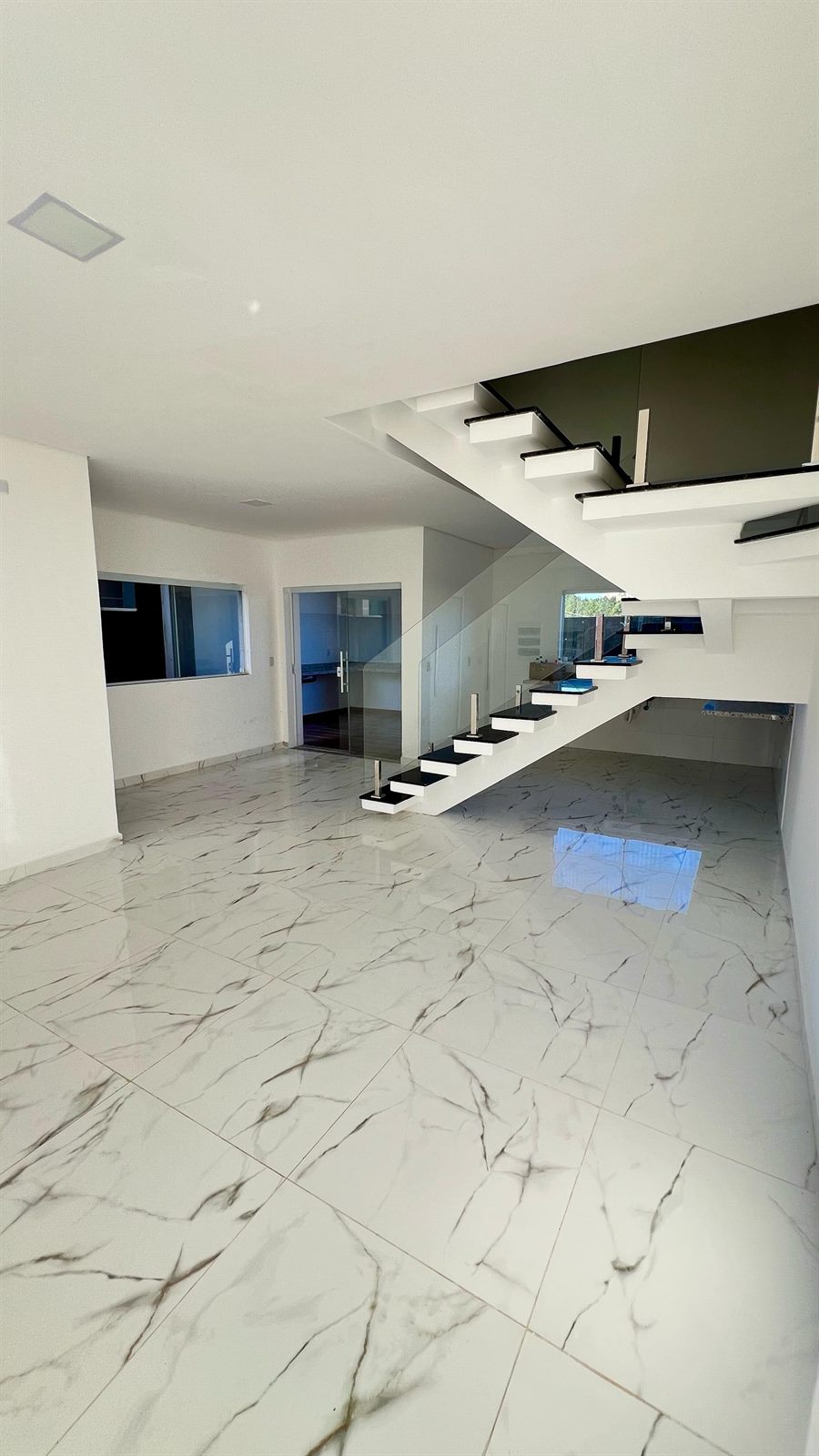 Sala ampla com escada e guarda-corpo de vidro